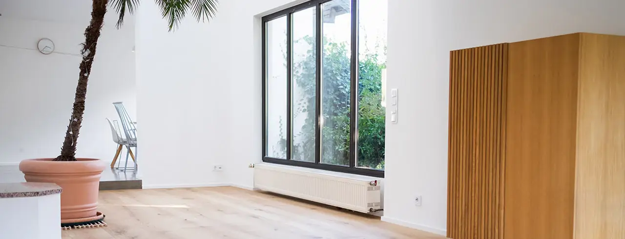 Einbauschrank aus Holz in einem hellen Raum mit Palme und bodentiefem Fenster