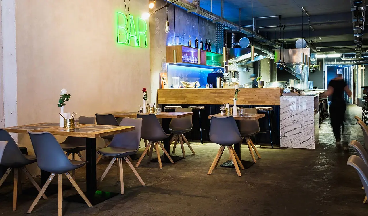 Bar mit grünem Neonlicht und Holztischen