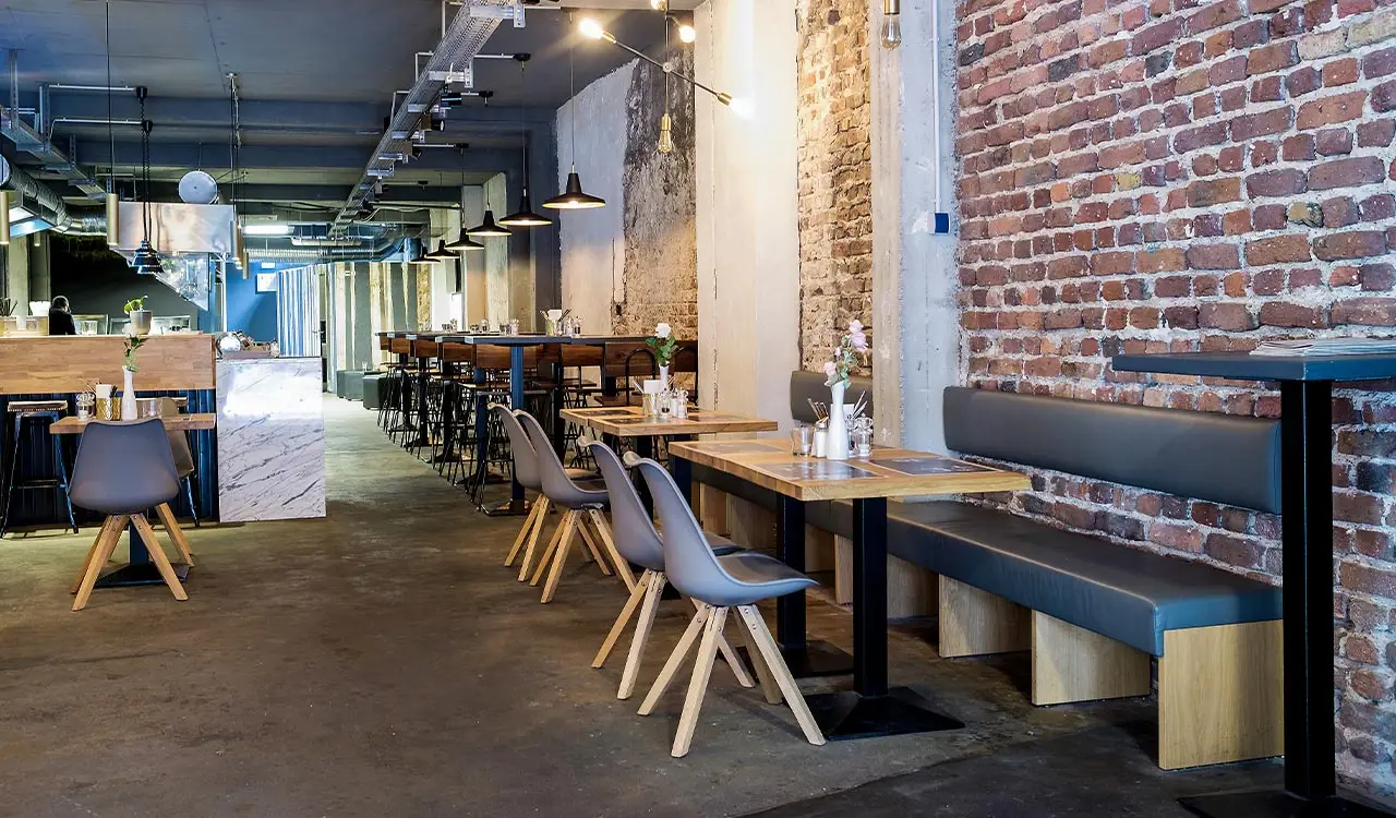 Gastraum des Restaurants Meat me mit Sitzbänken, Holztischen und Backsteinwand