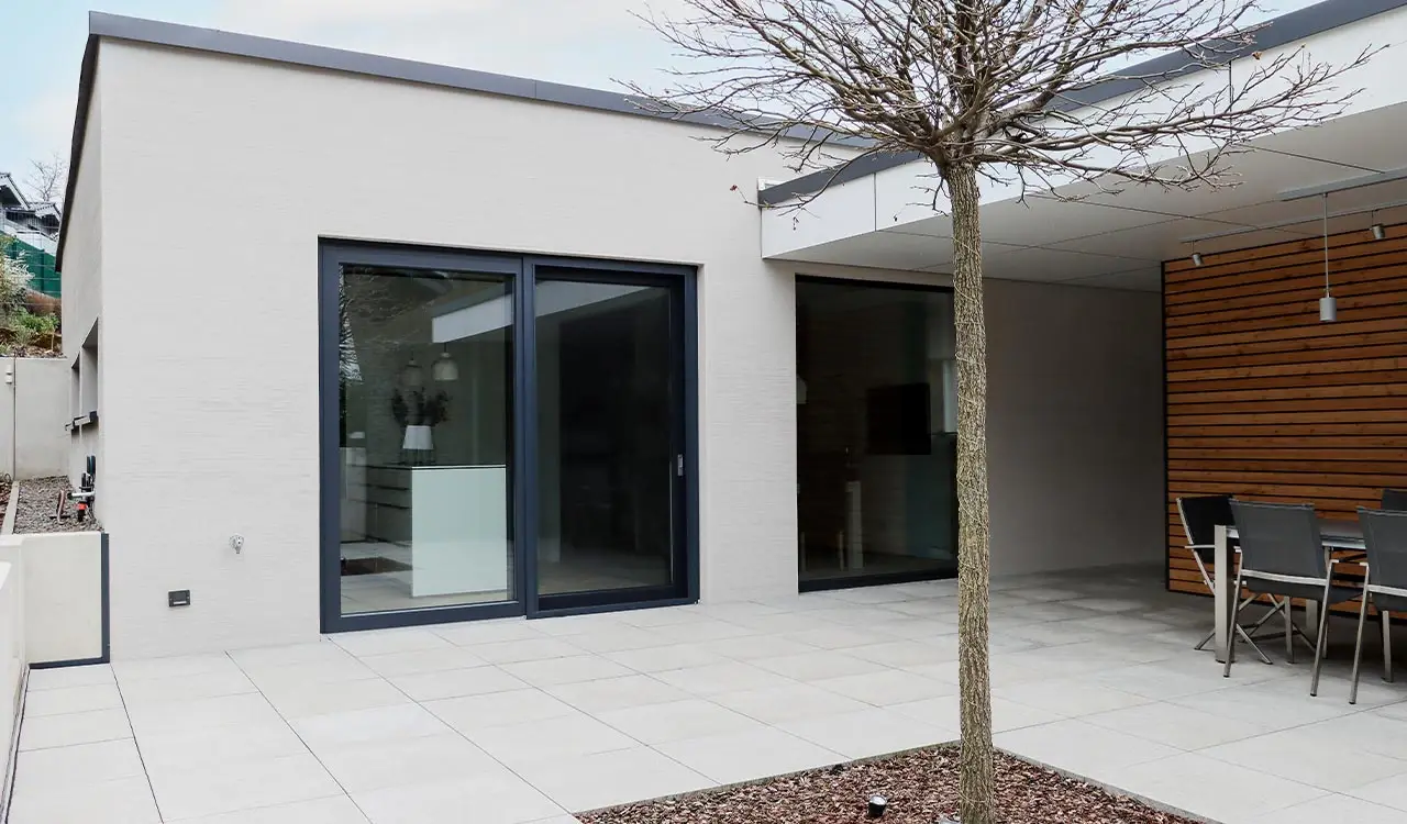 Terrasse mit Baum, Holzverkleidung und großen Schiebetüren