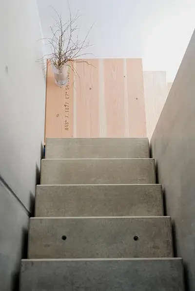 Sichtbetontreppe neben einer Wand aus hellem Holz